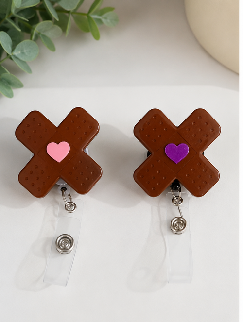 Brown bandages shaped in an “X”badge holders with heart designs on a white background and a person wearing blue scrubs with a registered nurse badge holder.
