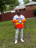 Person wearing an Astros jersey and colorful vest on a grassy area with a building in the background